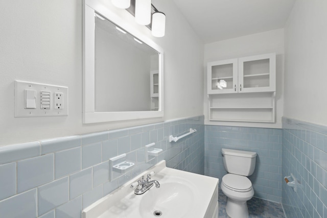 bathroom with vanity, wainscoting, toilet, and tile walls