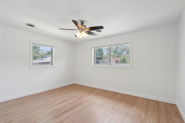 empty room featuring plenty of natural light, light wood-style floors, ceiling fan, and baseboards
