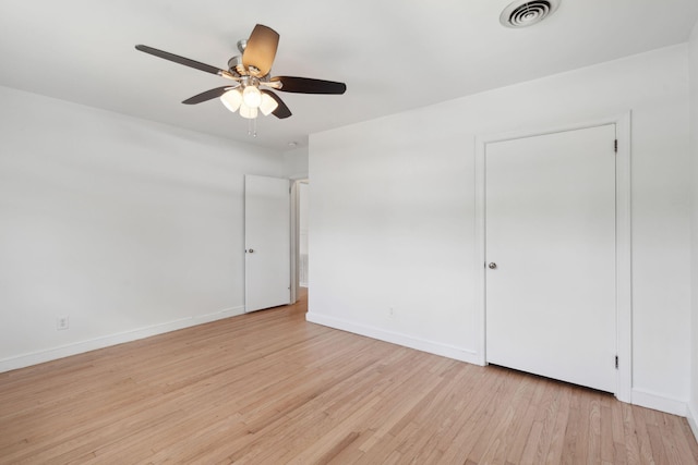 interior space featuring ceiling fan, visible vents, baseboards, and light wood finished floors