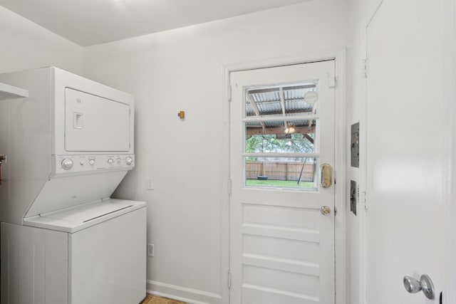 washroom with stacked washer / drying machine, baseboards, and laundry area