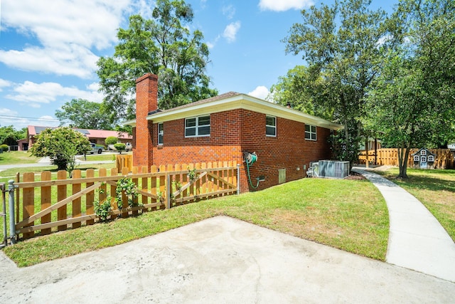 view of home's exterior with a yard, brick siding, a chimney, and fence private yard