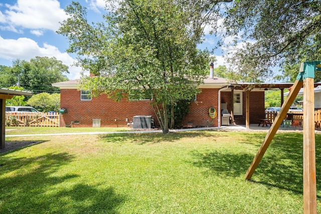 back of house with a lawn, fence, central air condition unit, and brick siding