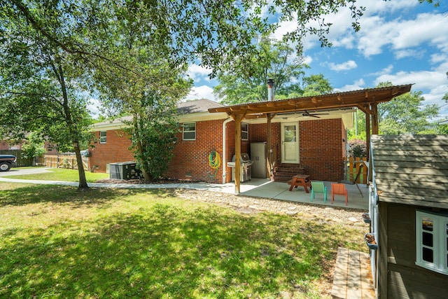 back of house featuring central air condition unit, brick siding, a lawn, a ceiling fan, and a patio