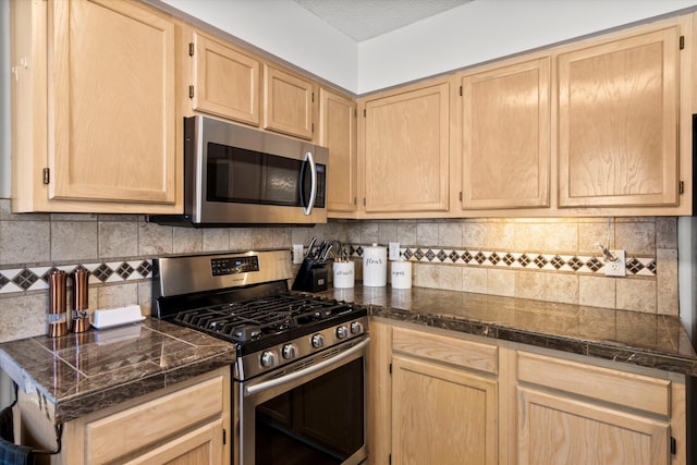kitchen featuring tile countertops, appliances with stainless steel finishes, decorative backsplash, and light brown cabinets