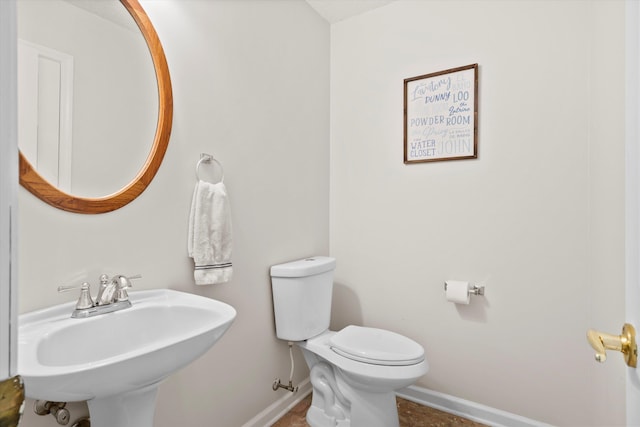 half bath with baseboards, a sink, and toilet
