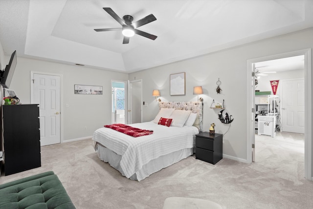 bedroom with visible vents, baseboards, ceiling fan, light colored carpet, and a tray ceiling