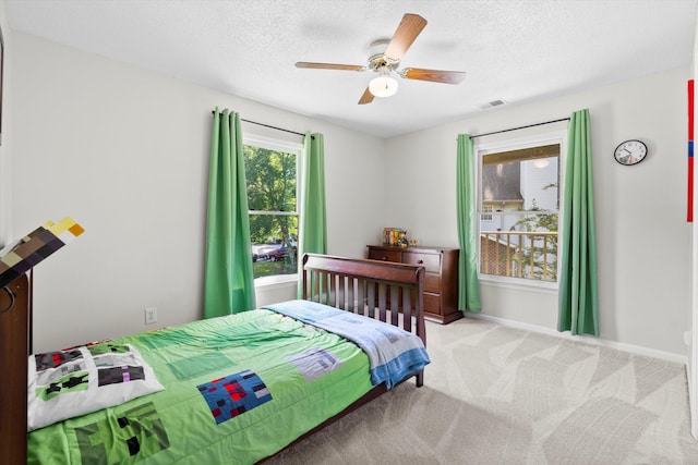 bedroom featuring a ceiling fan, a textured ceiling, light colored carpet, visible vents, and baseboards
