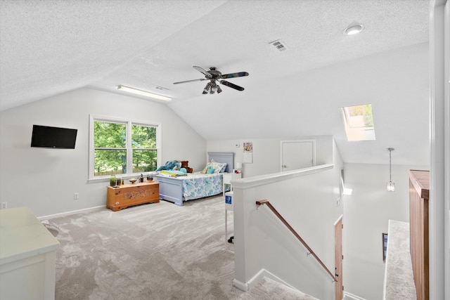 carpeted bedroom with vaulted ceiling with skylight, baseboards, a textured ceiling, and visible vents
