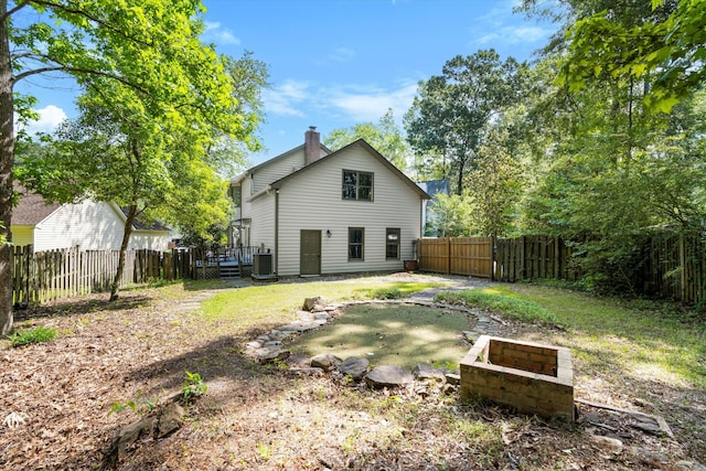 rear view of house featuring a fenced backyard, central AC, a chimney, and a deck