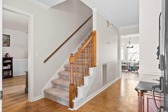 staircase featuring ornamental molding, wainscoting, and visible vents