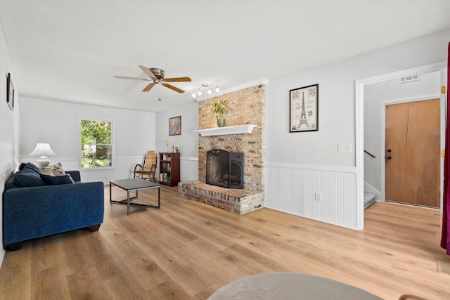 living area featuring visible vents, wood finished floors, stairway, a wainscoted wall, and a ceiling fan