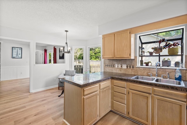 kitchen featuring plenty of natural light, tile countertops, light brown cabinetry, a sink, and a peninsula