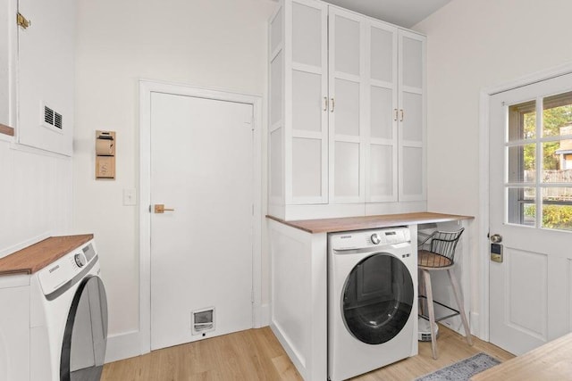 washroom featuring cabinets, washer / dryer, and light hardwood / wood-style flooring