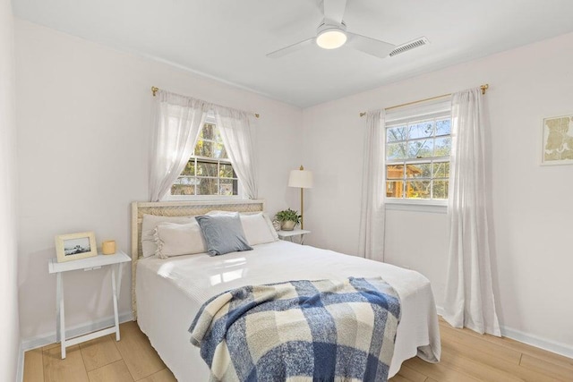 bedroom with multiple windows, ceiling fan, and light hardwood / wood-style floors