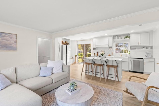 living room with ornamental molding, sink, a wealth of natural light, and light wood-type flooring