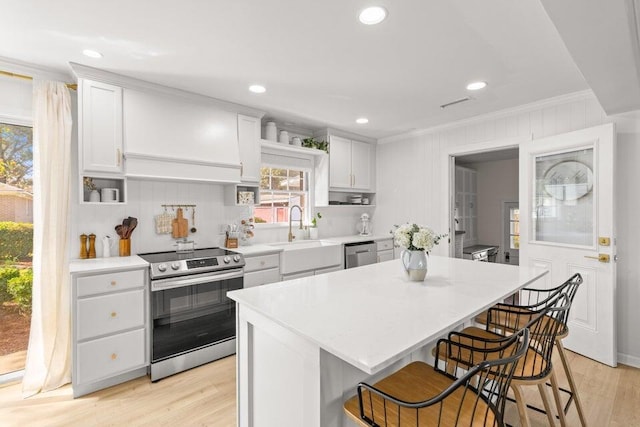 kitchen with crown molding, a breakfast bar, appliances with stainless steel finishes, a center island, and white cabinets