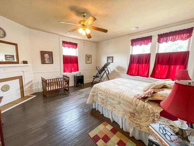 bedroom featuring multiple windows, a textured ceiling, dark hardwood / wood-style floors, and ceiling fan