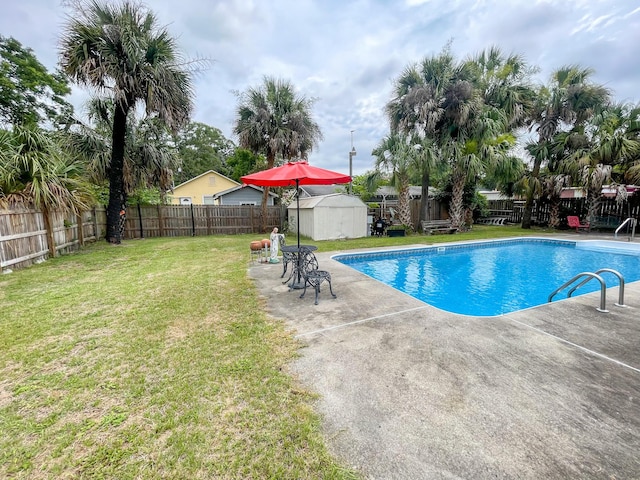 view of pool featuring a lawn, a patio, and a shed