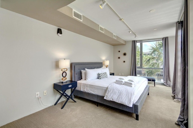 bedroom featuring floor to ceiling windows, visible vents, carpet flooring, and rail lighting