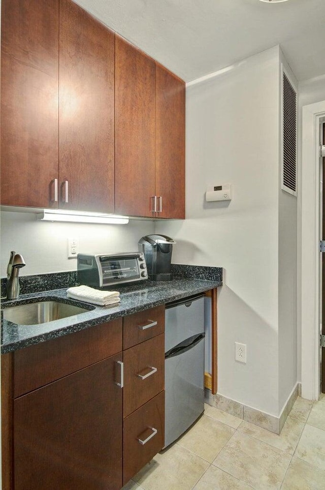 kitchen featuring a sink, fridge, dark stone countertops, and a toaster