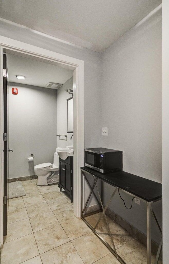 half bath with baseboards, toilet, and vanity