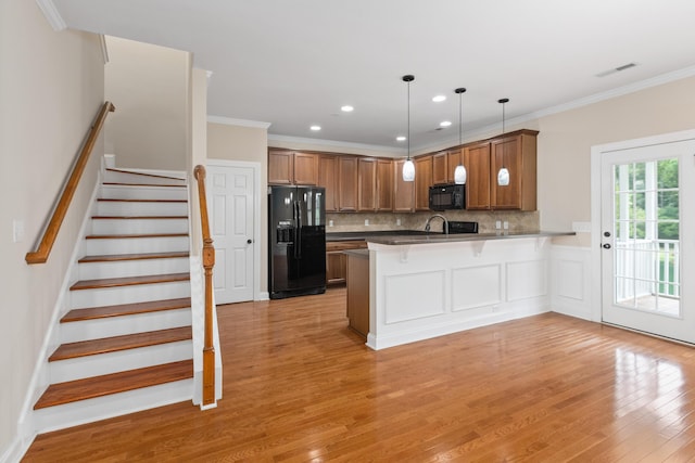 3588 Bagley Dr, Mount Pleasant, SC 29466 - kitchen featuring black appliances, a peninsula, light wood-type flooring, backsplash, and a kitchen bar