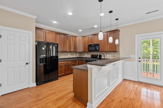 3588 Bagley Dr, Mount Pleasant, SC 29466 - kitchen with black appliances, a peninsula, brown cabinetry, light wood-style floors, and dark countertops