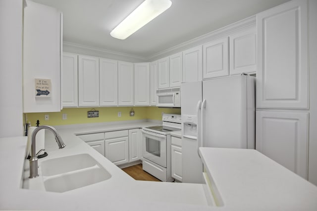 kitchen with light countertops, white appliances, white cabinetry, and a sink