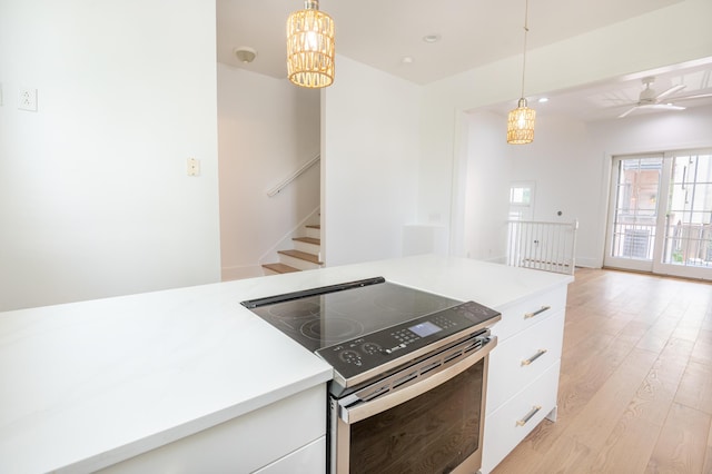 173 Coming St Unit B, Charleston, SC 29403 - kitchen with stainless steel electric stove, white cabinetry, light wood-style floors, a chandelier, and pendant lighting