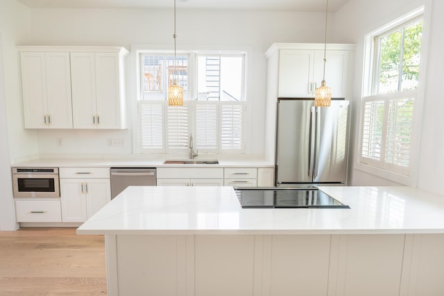 173 Coming St Unit B, Charleston, SC 29403 - kitchen with appliances with stainless steel finishes, light wood finished floors, white cabinetry, decorative light fixtures, and light countertops