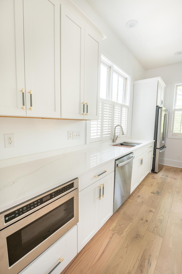 173 Coming St Unit B, Charleston, SC 29403 - kitchen featuring stainless steel appliances, light wood-type flooring, white cabinetry, and light stone countertops