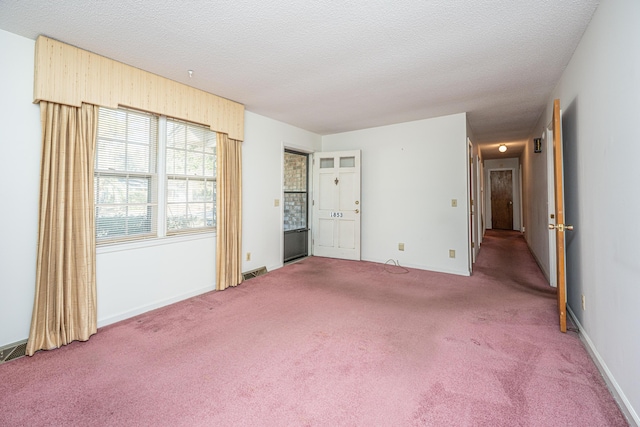 spare room featuring carpet floors, visible vents, a textured ceiling, and baseboards