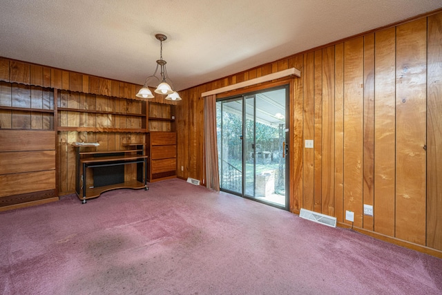 unfurnished living room with carpet flooring, wood walls, visible vents, and a fireplace