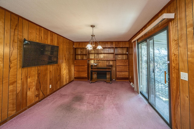 interior space featuring light carpet, wood walls, and a notable chandelier