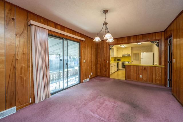 interior space with carpet floors, wooden walls, visible vents, and a textured ceiling