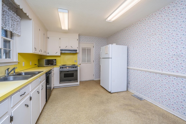 kitchen featuring range with electric stovetop, stainless steel microwave, freestanding refrigerator, white cabinets, and wallpapered walls