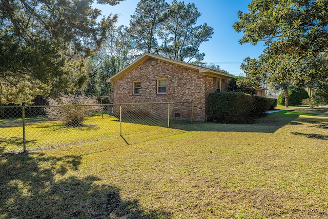 view of home's exterior with crawl space, brick siding, fence, and a yard