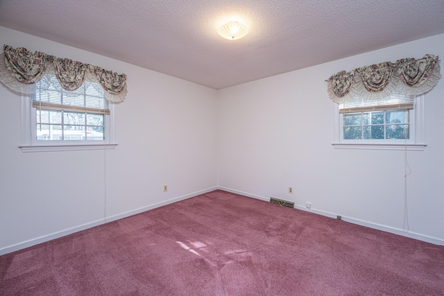 spare room with a textured ceiling, carpet, visible vents, and baseboards