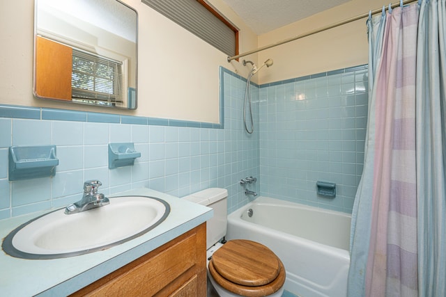 full bath with shower / bath combo, toilet, a textured ceiling, vanity, and tile walls