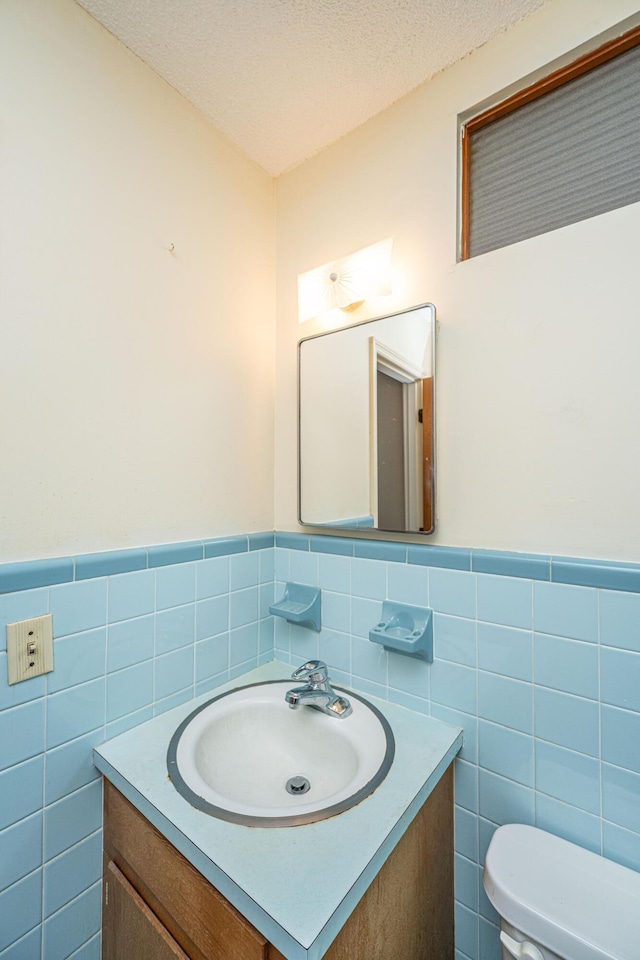 bathroom featuring toilet, a textured ceiling, and vanity