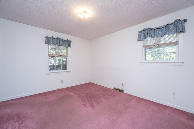 empty room featuring baseboards, visible vents, a textured ceiling, and carpet flooring