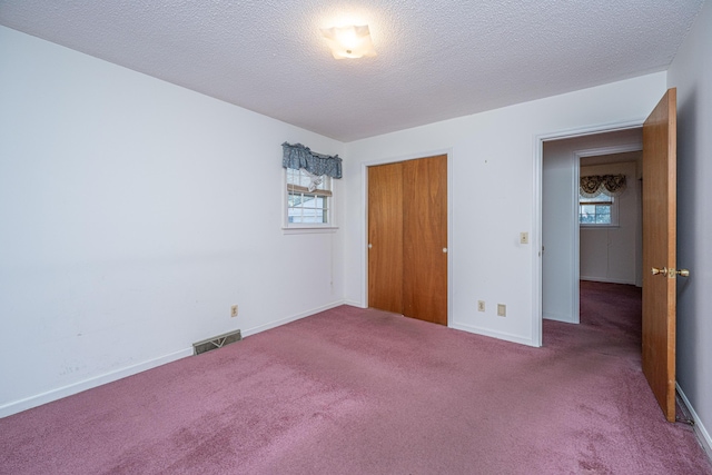 unfurnished bedroom featuring carpet floors, visible vents, and multiple windows