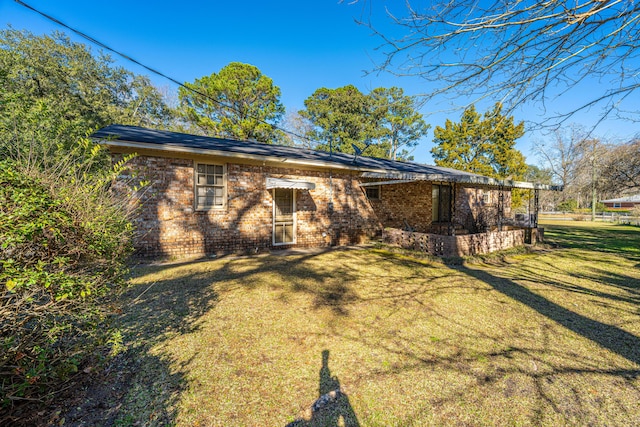 back of property with a lawn and brick siding