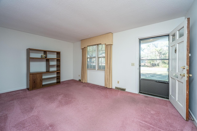 carpeted empty room featuring baseboards, visible vents, and a textured ceiling