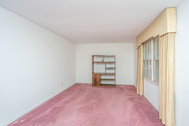 spare room with carpet floors, a textured ceiling, and baseboards