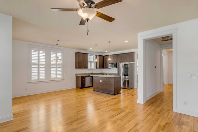 kitchen with light wood finished floors, a kitchen island, stainless steel appliances, light countertops, and dark brown cabinets