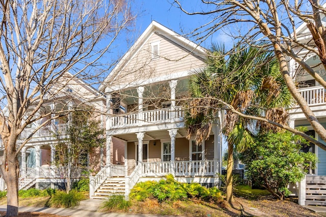 view of front facade with stairs, a balcony, and covered porch