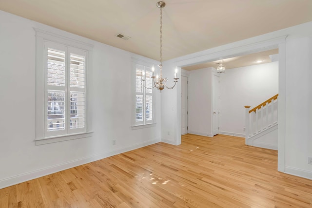 unfurnished dining area featuring visible vents, wood finished floors, an inviting chandelier, baseboards, and stairs