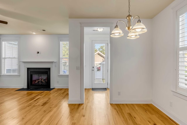 interior space with light wood finished floors, a fireplace with flush hearth, baseboards, and visible vents