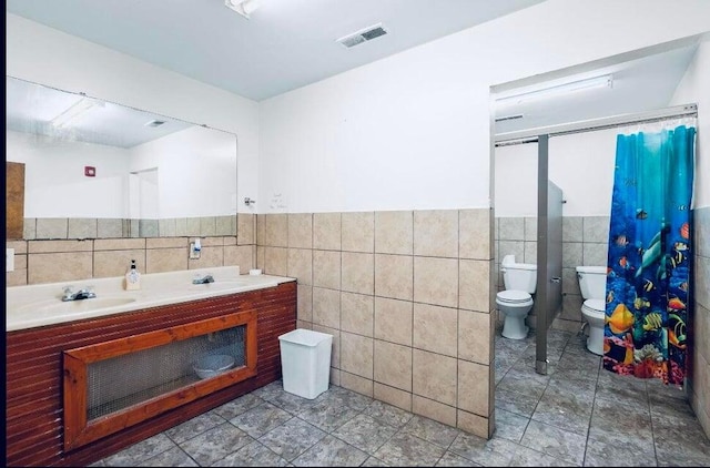 bathroom with vanity, toilet, tile patterned flooring, and tile walls